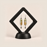 Autumn Sonata earrings displayed inside a black diamond-shaped frame on a rounded black base.