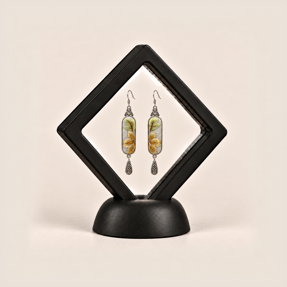 Autumn Sonata earrings displayed inside a black diamond-shaped frame on a rounded black base.