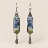Blue Reverie Suzhou Embroidery earrings with layered blue-gray petals and green leaves on pale gray panels, each with an engraved drop.