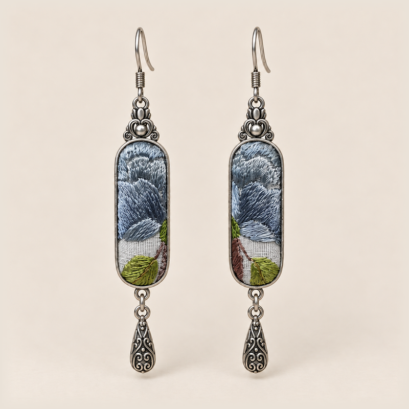 Blue Reverie Suzhou Embroidery earrings with layered blue-gray petals and green leaves on pale gray panels, each with an engraved drop.