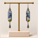 Blue Reverie earrings hanging from a gold-toned display stand with a pale rectangular base.