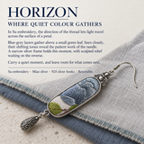 HORIZON story card with a Blue Reverie earring resting diagonally across layered gray and blue woven fabrics.