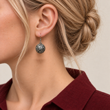 Indigo Cosmos round earring worn with the domed metal reverse and raised scrollwork facing outward.