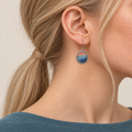 Coral Rhapsody earring worn with layered blue stitches and a coral-colored upper section facing outward.