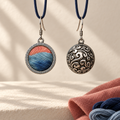 Coral Rhapsody earrings hanging from dark blue cord loops, one showing the embroidered front and the other the domed scrollwork reverse.
