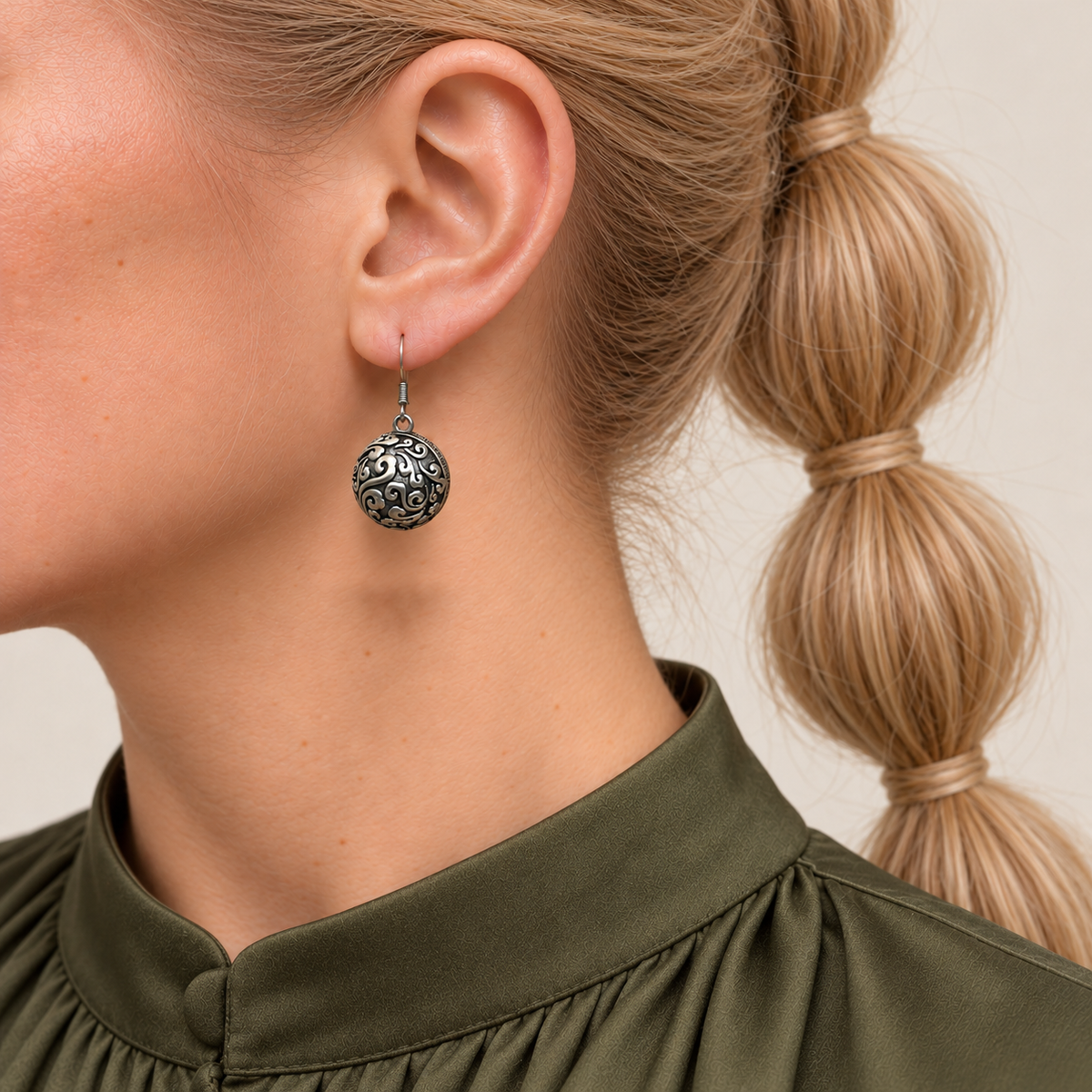 Verdant Bloom earring worn with the rounded metal reverse and raised scrollwork facing outward.