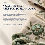 ORBIT culture card titled A Garden That Asks You to Slow Down, with green threads, an embroidered flower on pale cloth and a brush.