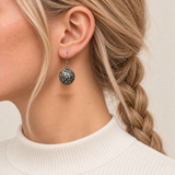 Sapphire Reverie earring worn with the rounded metal reverse and raised scrollwork facing outward.
