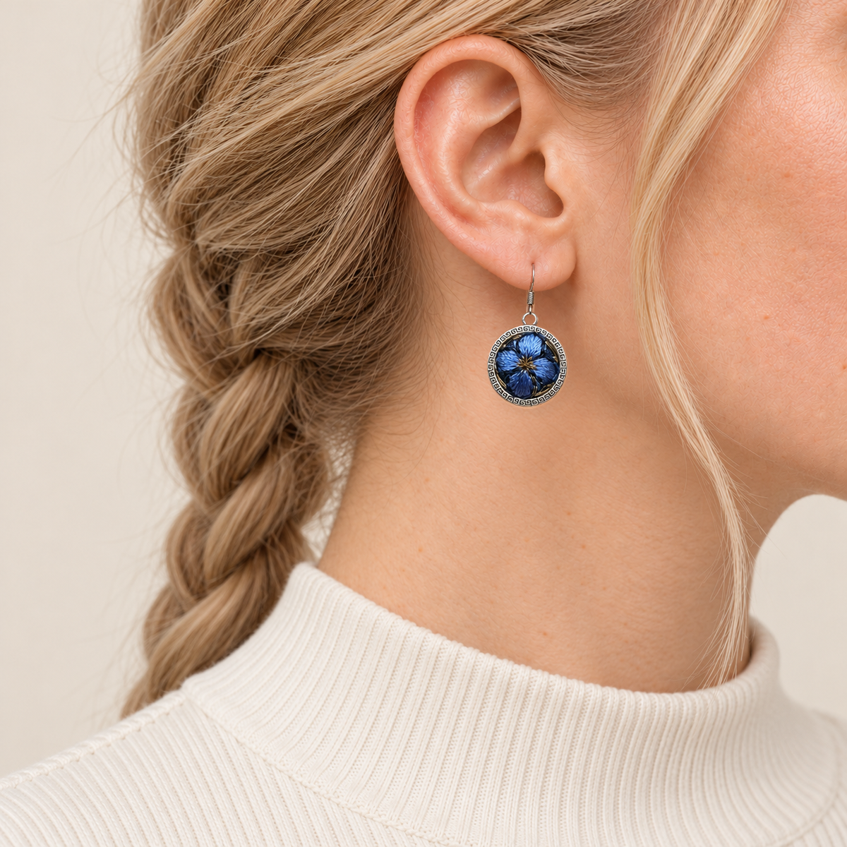 Sapphire Reverie earring worn with blue embroidered petals and a gold-colored center facing outward.
