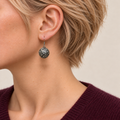 Jade Arabesque earring worn with the rounded metal reverse and raised scrollwork facing outward.