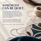 ORBIT culture card titled Strength Can Be Quiet, with raised pale outlines on embroidered cloth, thread, a needle and dark hair strands.