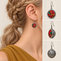 Crimson Cadence earring worn with its embroidered front facing outward, beside front, 45-degree and domed reverse views.