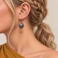 Crimson Cadence earring worn with the rounded metal reverse and raised scrollwork facing outward.