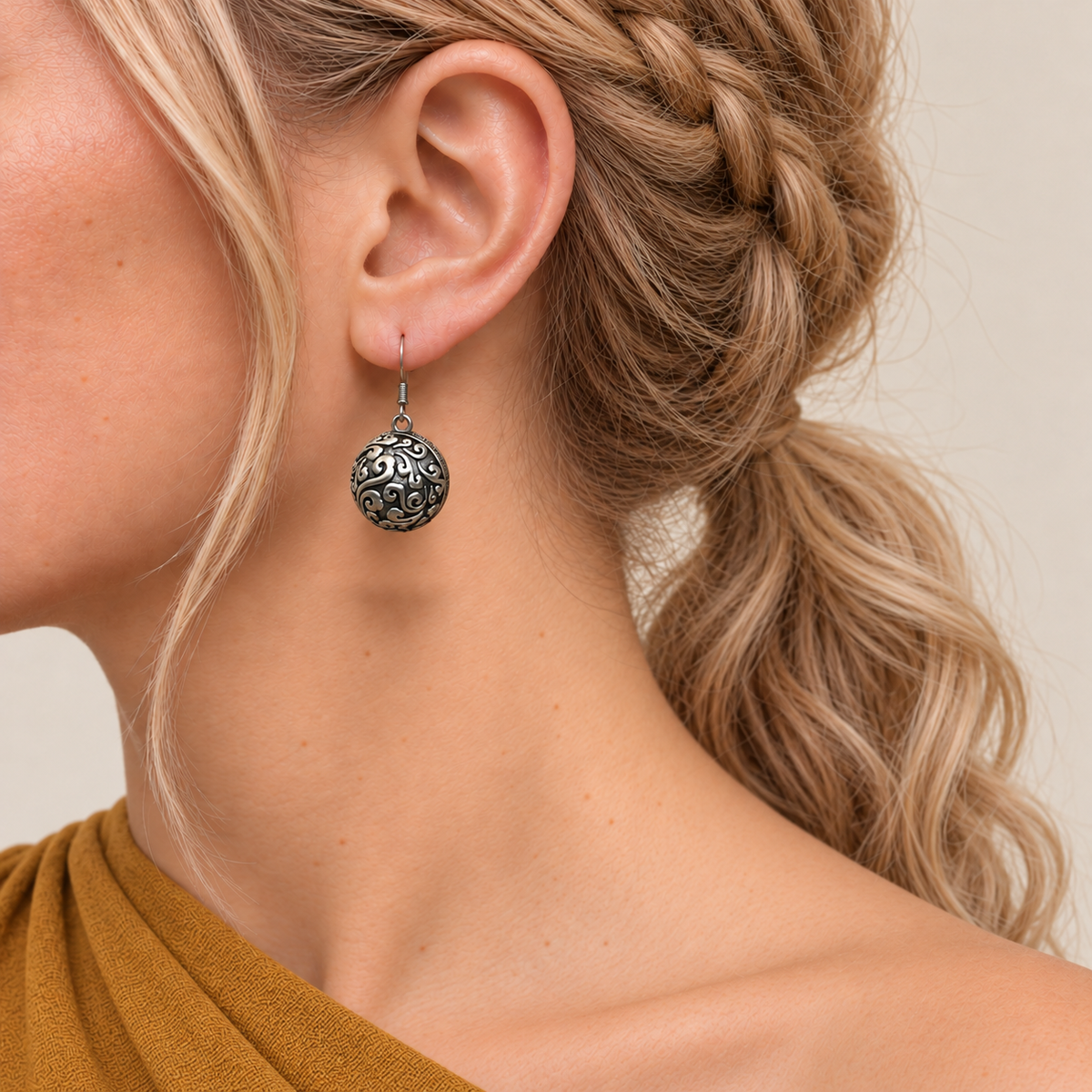 Crimson Cadence earring worn with the rounded metal reverse and raised scrollwork facing outward.