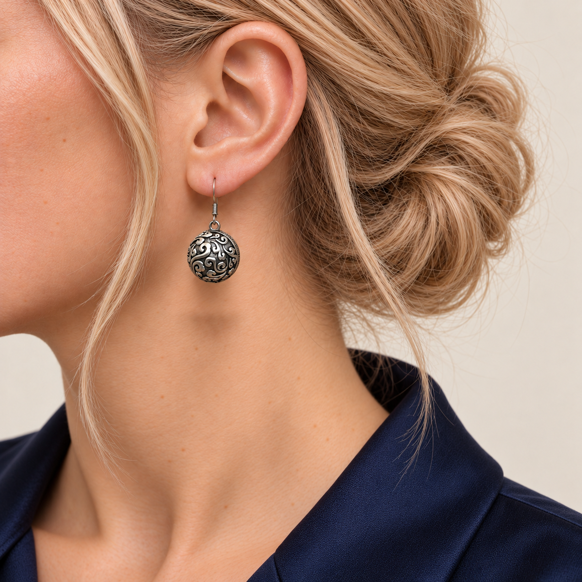 Forest Lustre earring worn with the rounded metal reverse and raised scrollwork facing outward.