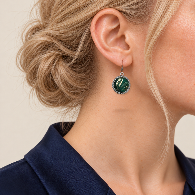 Forest Lustre earring worn with green and pale gold-colored woven forms on its circular front facing outward.