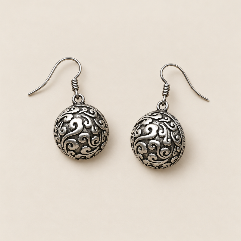 Forest Lustre earrings laid back-facing on a pale surface, showing domed metal backs with raised curling patterns.