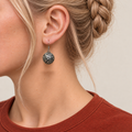 Rosy Aubade earring worn with the rounded metal reverse and raised scrollwork facing outward.