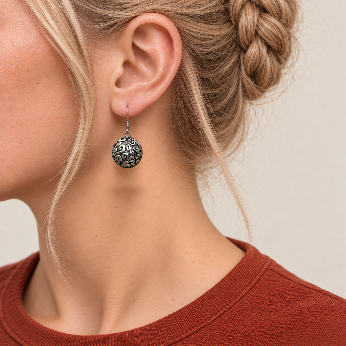 Rosy Aubade earring worn with the rounded metal reverse and raised scrollwork facing outward.