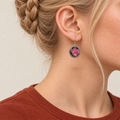 Rosy Aubade earring worn with pink and pale embroidered petals and gold-colored outlines facing outward.