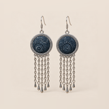 Indigo Canticle Batik earrings with pale radial and curling motifs on indigo textile, round patterned rims and five chains ending in teardrops on each earring.
