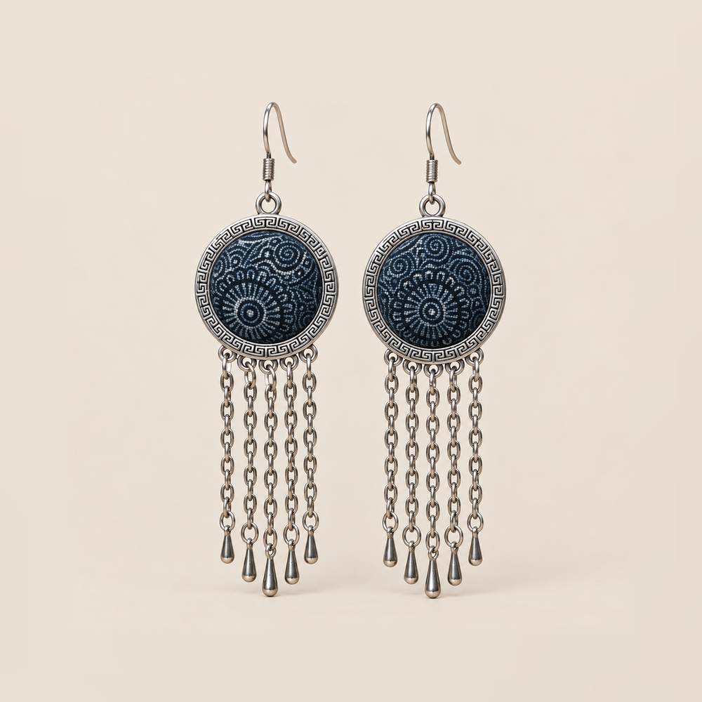 Indigo Canticle Batik earrings with pale radial and curling motifs on indigo textile, round patterned rims and five chains ending in teardrops on each earring.