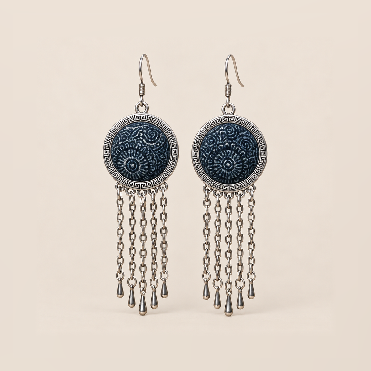Indigo Canticle Batik earrings with pale radial and curling motifs on indigo textile, round patterned rims and five chains ending in teardrops on each earring.