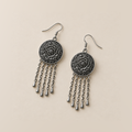 Indigo Canticle earrings laid back-facing, showing layered flower relief on the round metal backs and five chain tassels on each.
