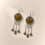 Golden Benediction earrings laid front-facing, showing golden-yellow geometric embroidery, cloud charms and central plaques inscribed 纳福.