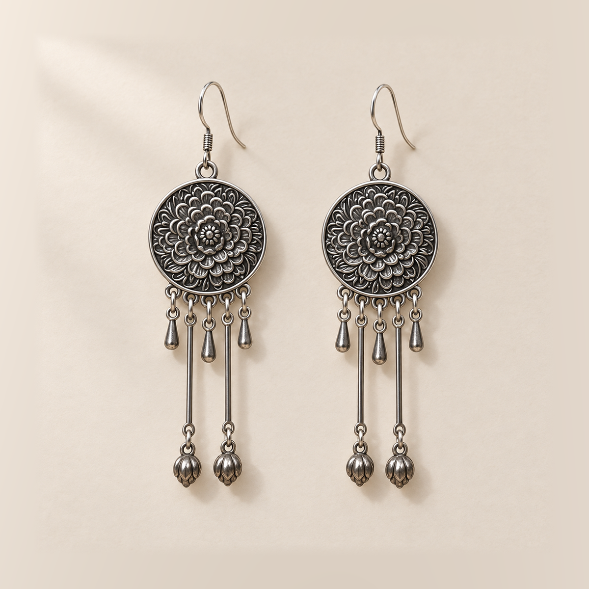 Amber Floraison earrings laid back-facing, showing flower relief on the round medallions, three short drops and two long rods with bud pendants on each.