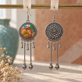 Amber Floraison earrings hanging from pale woven strips on a gold-colored bar, showing the embroidered flower front and flower relief reverse.