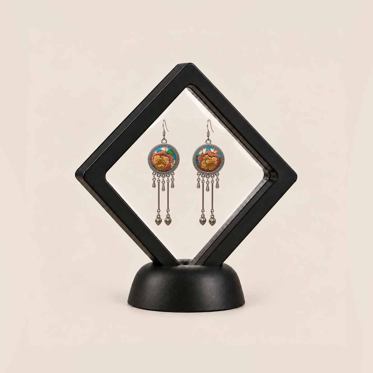 Amber Floraison earrings displayed inside a clear membrane in a black square frame set diagonally on a black base.