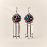 Pastel Refrain earrings with pink, teal and pale counted-thread geometric embroidery on dark round medallions, each with five rods ending in three teardrops and two round beads.