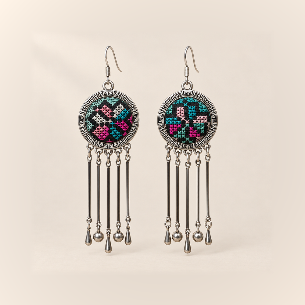 Pastel Refrain earrings with pink, teal and pale counted-thread geometric embroidery on dark round medallions, each with five rods ending in three teardrops and two round beads.