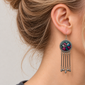 Model in profile wearing Pastel Refrain with pastel counted-thread geometric embroidery facing outward above five dangling rods.