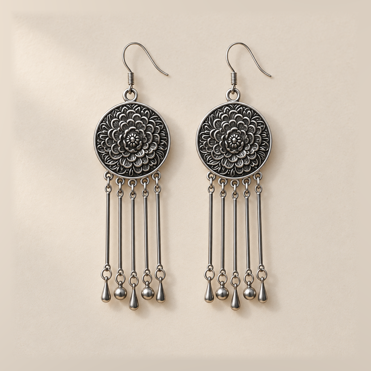 Pair of Pastel Refrain earrings laid flat with floral metal reverses facing up, each with five rods ending in teardrop, round, teardrop, round and teardrop shapes.