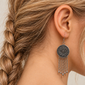 Model with a loose side braid wearing Violet Undertow with the floral metal reverse facing outward above five chain tassels with teardrop ends.