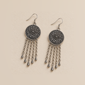 Violet Undertow pair laid flat with round floral metal reverses facing up, each with five linked tassels ending in teardrop pendants.