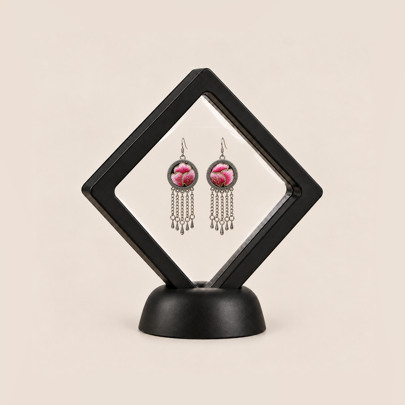 Blush Rhapsody pair displayed in a black square clear-membrane frame on a black stand, with both pink embroidered fronts facing forward.