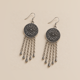 Garnet Serenade pair laid flat with round floral metal reverses facing up, each with five linked tassels ending in teardrop pendants.