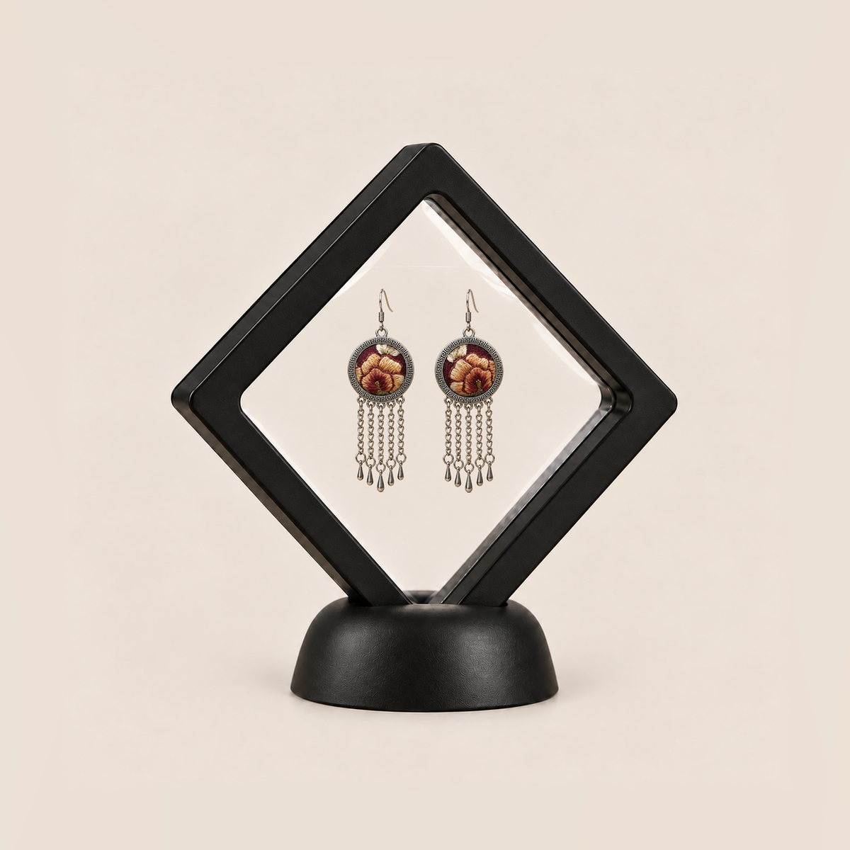 Garnet Serenade pair displayed in a black square clear-membrane frame on a black stand, with both warm floral embroidered fronts facing forward.