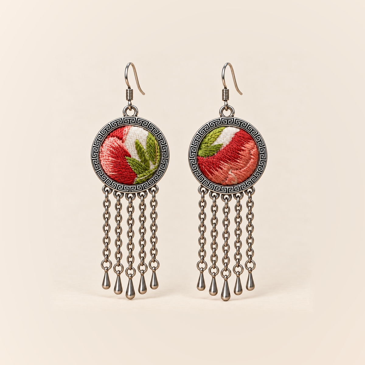 Coral Reverie earrings with coral-red and pink embroidered petals and green leaves on ivory-colored round fronts, each with five oval-link chains and teardrop ends.