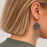 Model with a short bob wearing Coral Reverie with the round floral metal reverse facing outward above five oval-link chains with teardrop pendants.