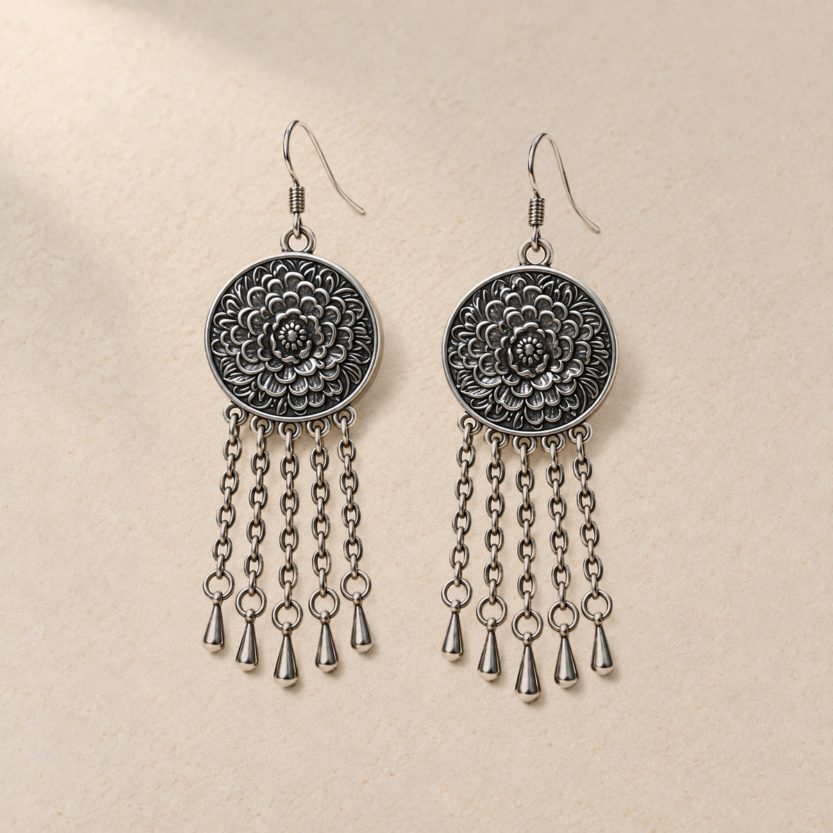 Coral Reverie pair laid flat with round floral metal reverses facing up, each with five oval-link chains ending in teardrop pendants.