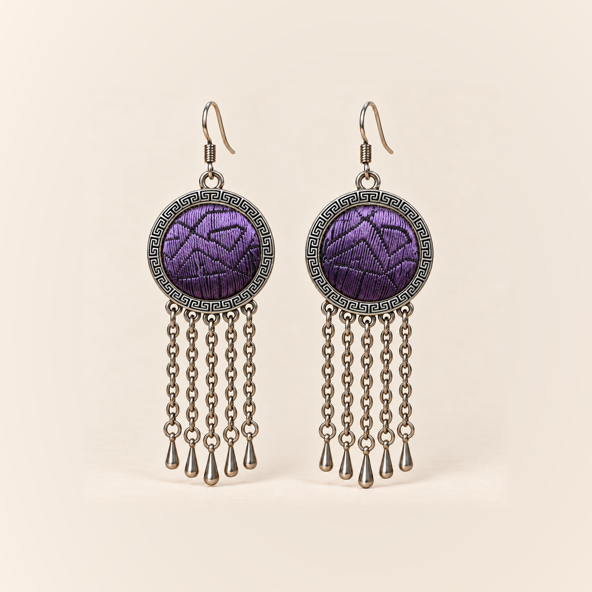 Violet Cadence earrings with purple counted-thread embroidery and dark angular outlines in round patterned frames, each with five oval-link chains and teardrop pendants.
