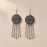 Violet Cadence pair laid flat with round floral metal reverses facing up, each with five oval-link chains ending in teardrop pendants.
