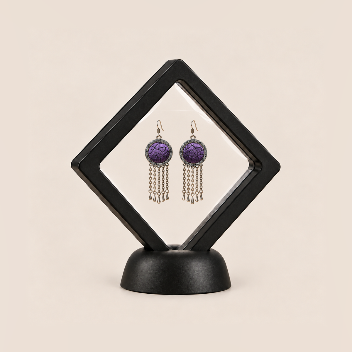 Violet Cadence pair displayed in a black square clear-membrane frame on a black stand, with both purple geometric embroidered fronts facing forward.
