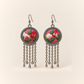 Petal Dialogue earrings with red and white embroidered petals and green leaves on pink round fronts, each with five oval-link chains ending in three teardrops and two spheres.