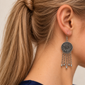 Model with a high ponytail wearing Petal Dialogue with the floral metal reverse facing outward above five chains with alternating teardrop and spherical ends.