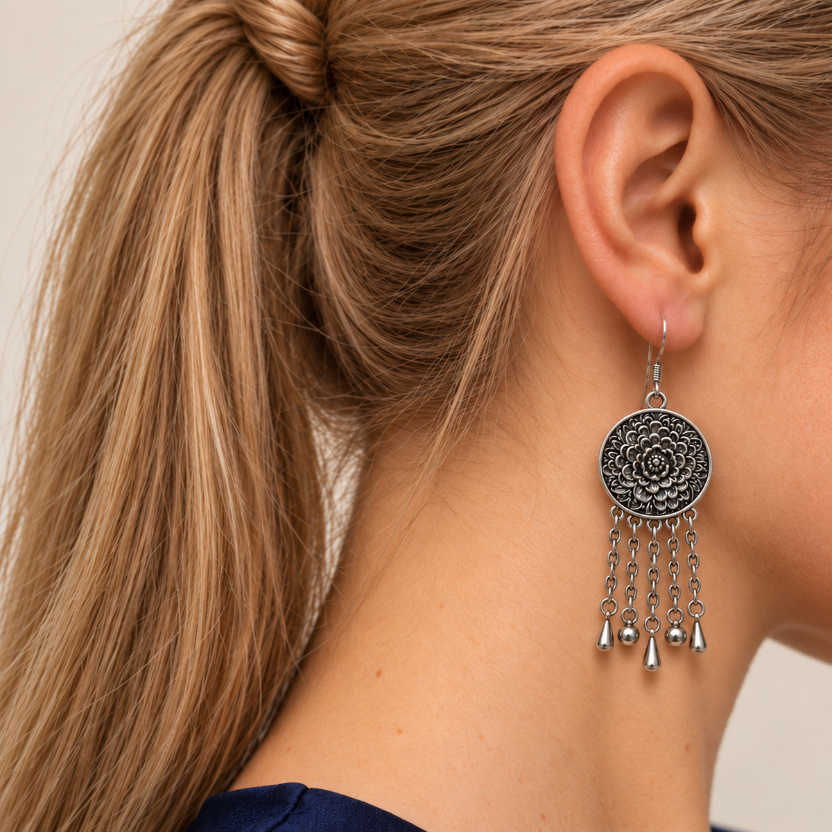Model with a high ponytail wearing Petal Dialogue with the floral metal reverse facing outward above five chains with alternating teardrop and spherical ends.